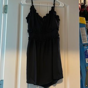 Black romper with ruffle detail and adjustable straps. Never worn.